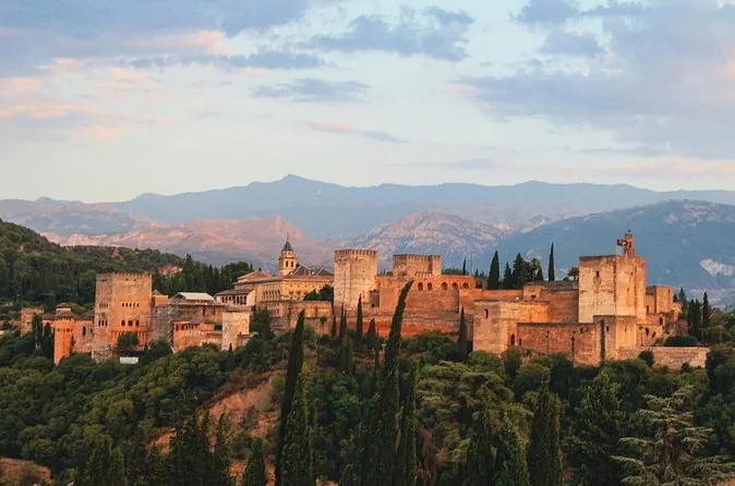 Panorama of the Alhambra on its wooded hill with the mountains behind